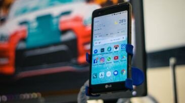 LG Android smartphone in a holder displaying its apps.